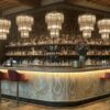 vintage curved onyx stone bar counter with arched metal wine rack for retro restaurant and whiskey lounge