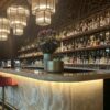 vintage curved onyx stone bar counter with arched metal wine rack for retro restaurant and whiskey lounge