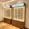 optical cabinets (21) Wood Grain Lockable Glass Eyewear Display Cabinet | LED Lighted Tall Sunglasses Showcase With Top Backlit Logo Sign & Lower Secure Storage Cupboard For Optical Retail Shops
