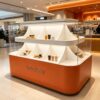 retail display stands (11) Orange white glossy two-tier curved sector divided island display cabinet with clear glass Lexio Display for café bakery beverage retail mall showcase