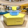 retail display stands (21) Hexagonal three-tier LED edge lighted island display stand glossy yellow blue with storage cabinet Lexio Display for shopping mall pop-up and product promotion