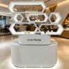 White glossy honeycomb hexagon LED lighted retail island display stand curved base Lexio Display for mall café and beverage product pop-up promotion
