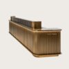 Fluted antique brass L-shaped reception desk with dark marble top and LED ambient light, luxury office lobby front counter Lexio Display for high-end corporate interior