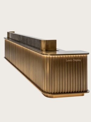 Fluted antique brass L-shaped reception desk with dark marble top and LED ambient light, luxury office lobby front counter Lexio Display for high-end corporate interior