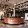 U‑shape curved reception desk with vertical panel aged patina copper cladding, vintage industrial‑style lobby front counter Lexio Display for loft and commercial space
