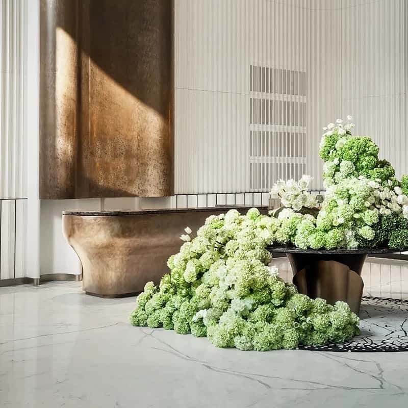 Brushed bronze curved reception desk with natural marble top, solid‑body luxury lobby counter Lexio Display for premium hotel and corporate project