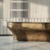 Brushed bronze curved reception desk with natural marble top, solid‑body luxury lobby counter Lexio Display for premium hotel and corporate project