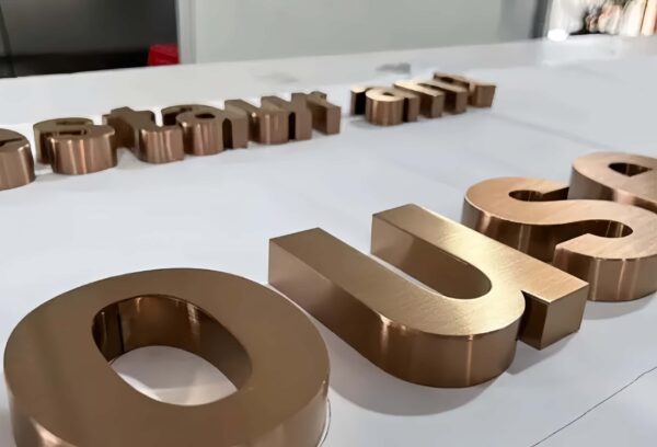 Thin brushed bronze metal letters with mounting studs for wall installation
