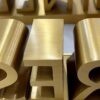 Bulk custom brushed gold 3D solid metal letters laid flat for quality inspection