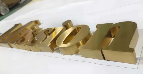 Mirror gold 3D metal brand logo letters floating on white reception wall