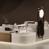 Side view custom shopping centre handbag booth with black metal arched mirror frame, display handbags and leather accessories