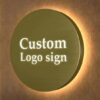 Close-up view of circular gold backlit metal sign with illuminated custom logo letters