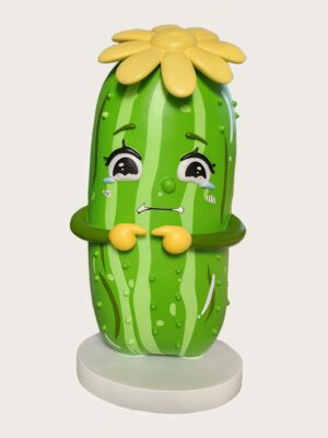 Factory shot cartoon cucumber fiberglass mascot sculpture with crying face, yellow flower on top, paired with red chili character statue in workshop