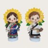 Studio photo of twin ethnic kids fiberglass mascot sculptures, girl and boy in traditional ethnic costume with large sunflower backdrop, standing on light blue round bases