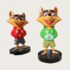 Factory workshop photo of two cartoon raccoon fiberglass mascot sculptures, red hoodie and green hoodie raccoon characters standing on black round bases