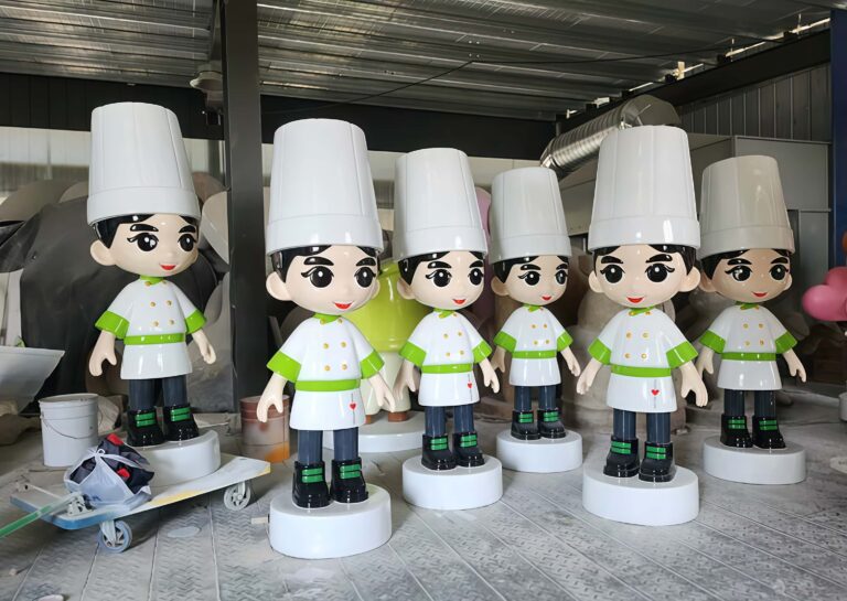Factory workshop photo of batch cartoon chef fiberglass mascot sculptures, chibi chef characters with tall white chef hats and green trimmed chef coats