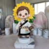 Customized fiberglass display (7) Front view glossy FRP cultural IP statue pair, cute chibi ethnic children with traditional folk clothing and sunflower decor for tourist scenic spot photo corner